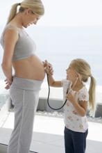 เด็กหญิงใช้หูฟังของแพทย์ฟังเสียงของหญิงมีครรภ์
