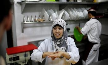 A hearing impaired employee uses sign language to communicate with a co-worker in the kitchen of Atfaluna restaurant in Gaza City, Oct. 17, 2012. (photo by REUTERS/Suhaib Salem )