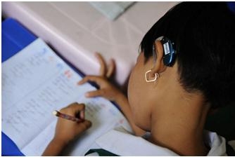 เด็กหญิงพิการหูหนวก ใช้เครื่องช่วยฟังกำลังนั่งทำการบ้าน
