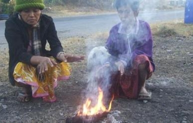 ชาวบ้านนั่งผิงไฟบรรเทาความหนาวเย็น