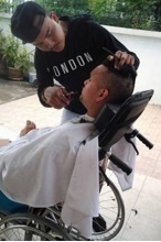 นายกอล์ฟ กำลังให้บริการตัดผมฟรี แด่คนพิการถึงที่บ้าน