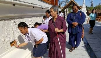 เด็กๆพิการทางสายตาสัมผัสประติมากรรมปูนปั้นนูนต่ำรอบโบสถ์วัดเขาย้อย พร้อมอักษรเบรลล์บรรยายชื่อรูป