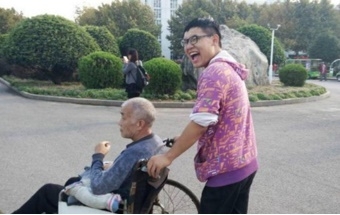 นายจ้าว เต๋อหลง เข็นรถวีลแชร์ให้พ่อ